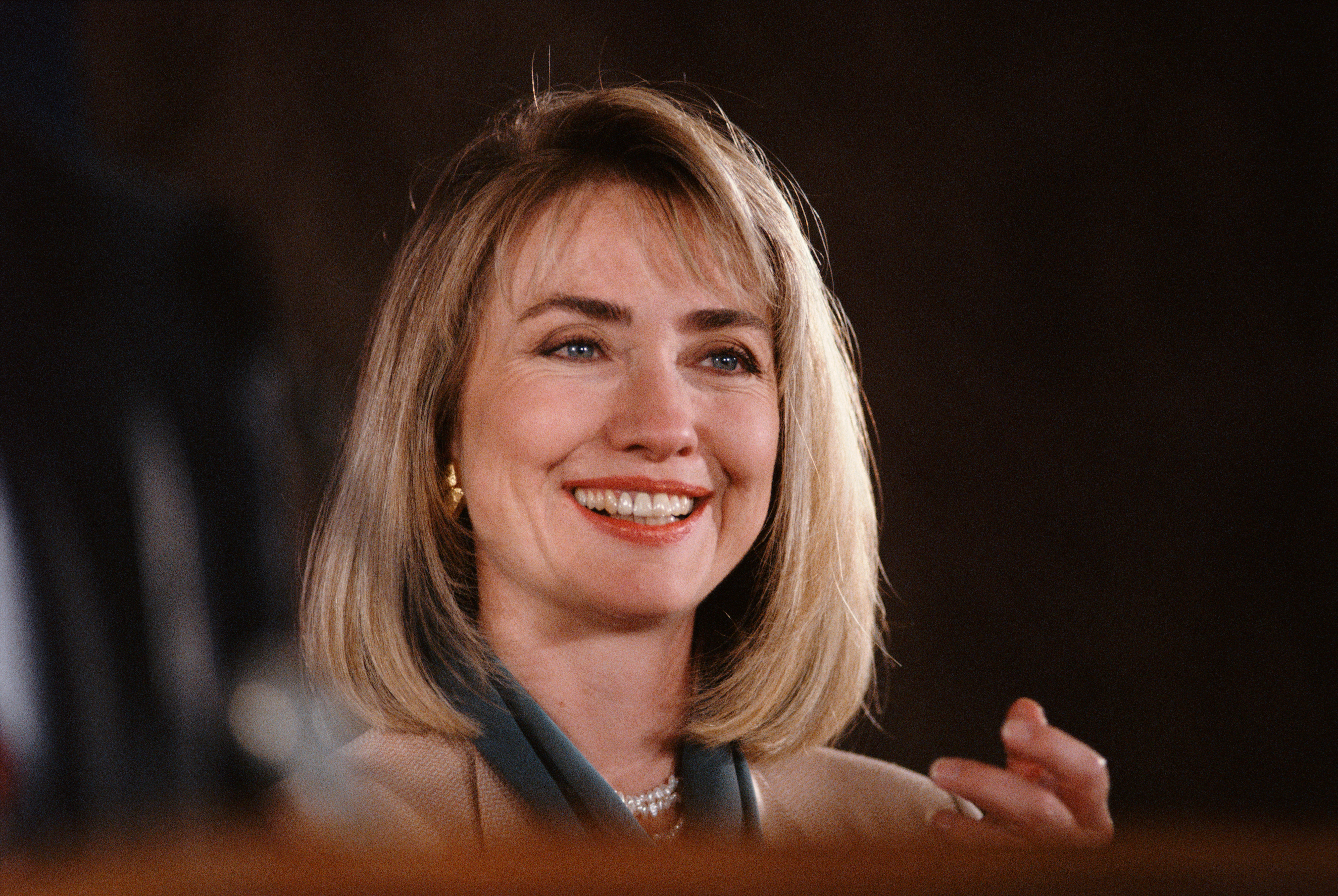 Smiling woman with shoulder-length hair wearing a blazer and pearl necklace