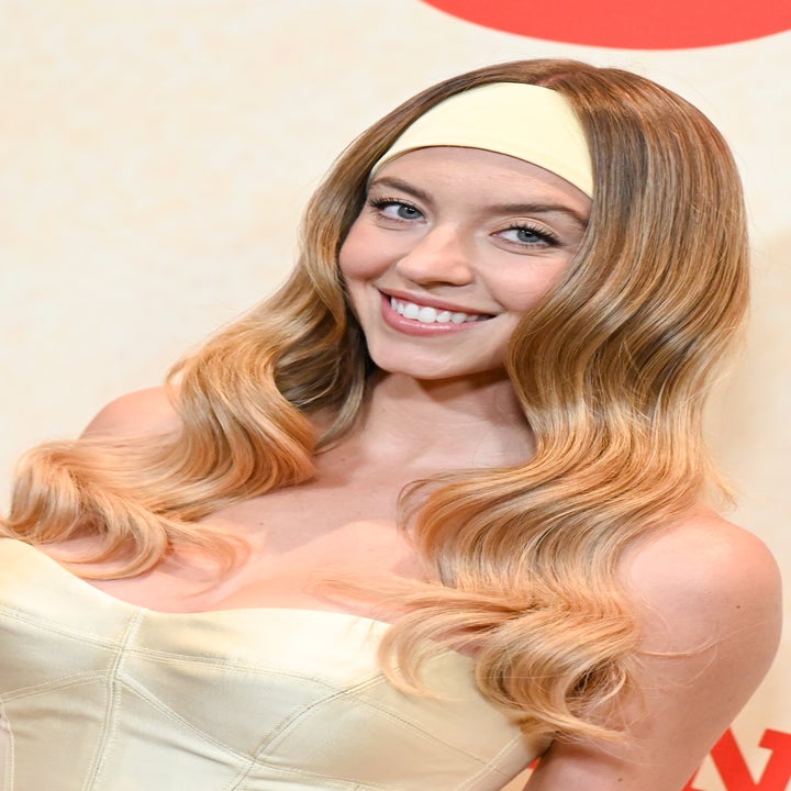 Woman on red carpet wears strapless dress with voluminous hairband