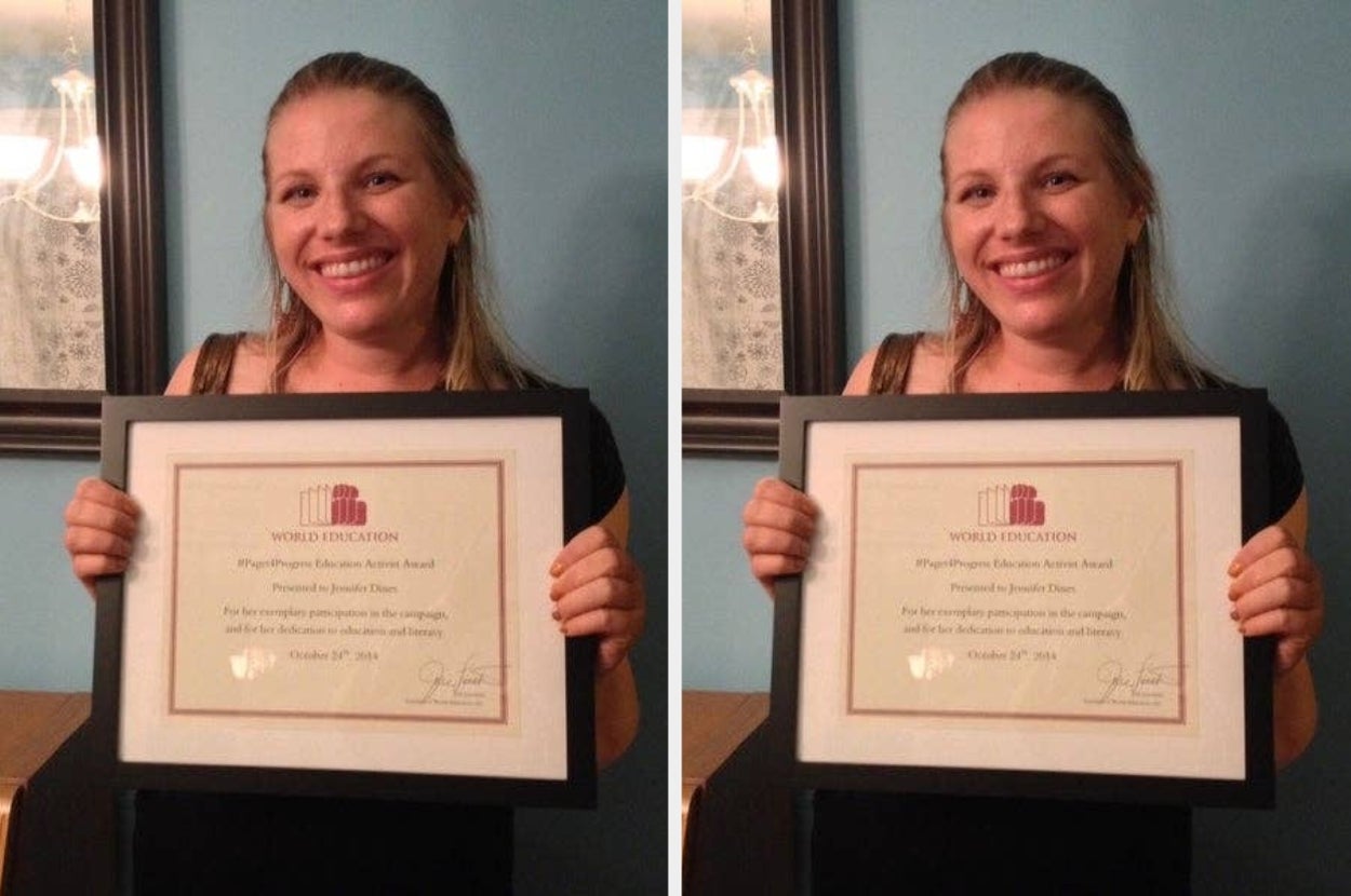 Smiling woman holding an award certificate for professional excellence, framed in black, standing indoors