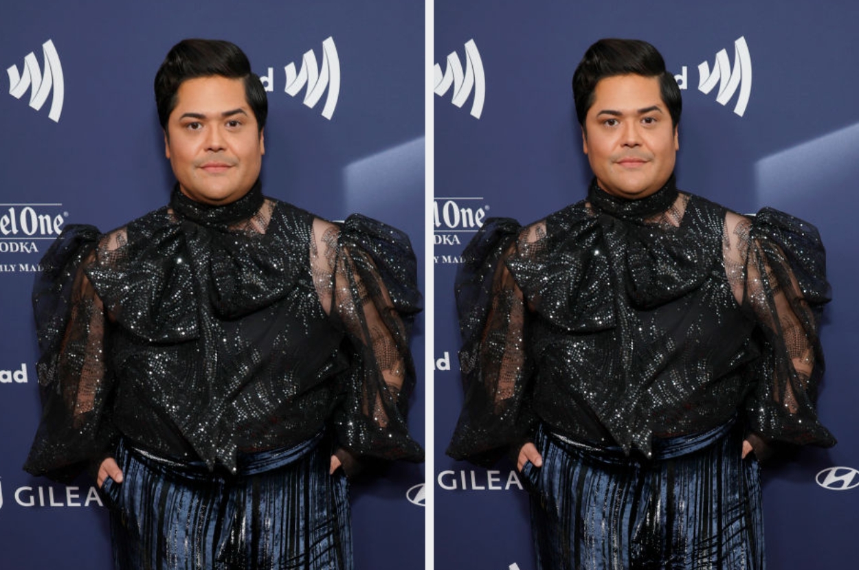 Person in a shimmering, textured top and striped pants on a red carpet at a celebrity event