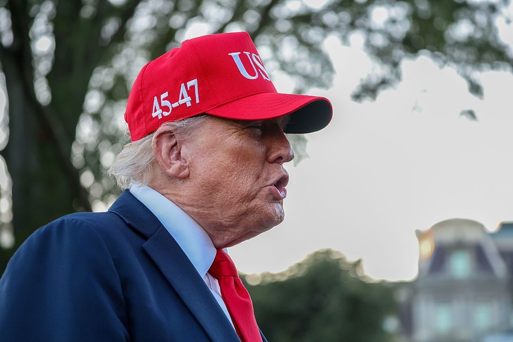 Person i dress med rød lue med «45-47»; stående utendørs, trær i bakgrunnen