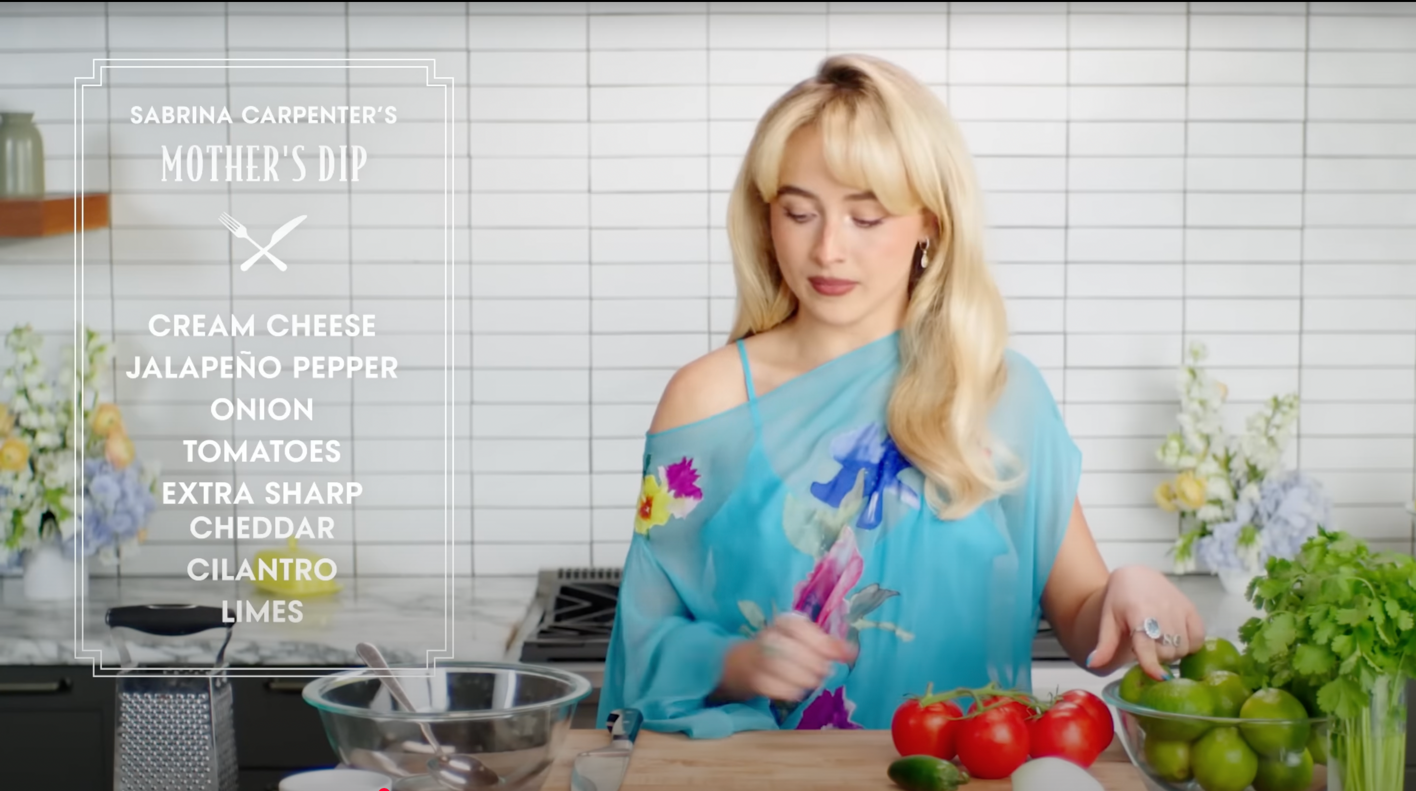 A person in a floral dress prepares ingredients in a kitchen. Text lists: cream cheese, jalapeño, onion, tomatoes, cheddar, cilantro, limes