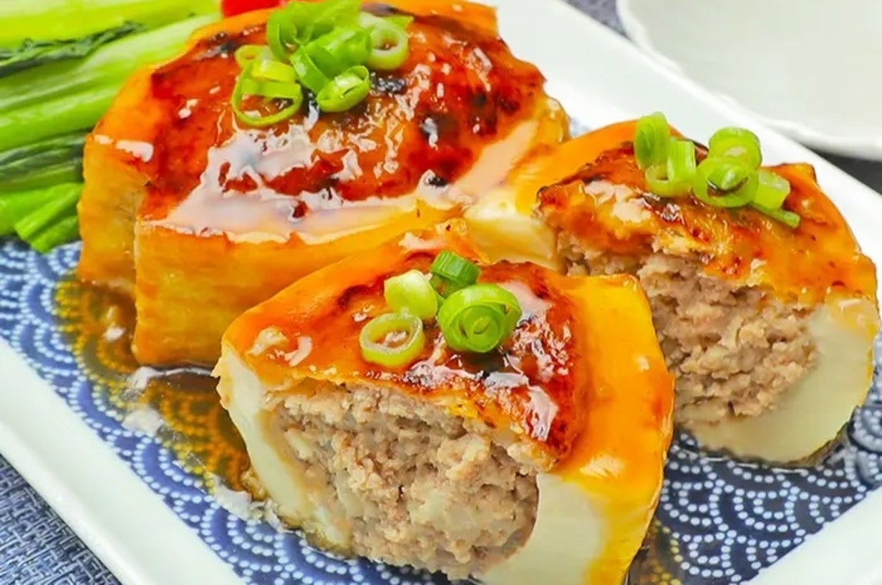 お皿に盛られた肉詰め野菜の料理。上に青ネギがかかり、添え野菜が横にある。