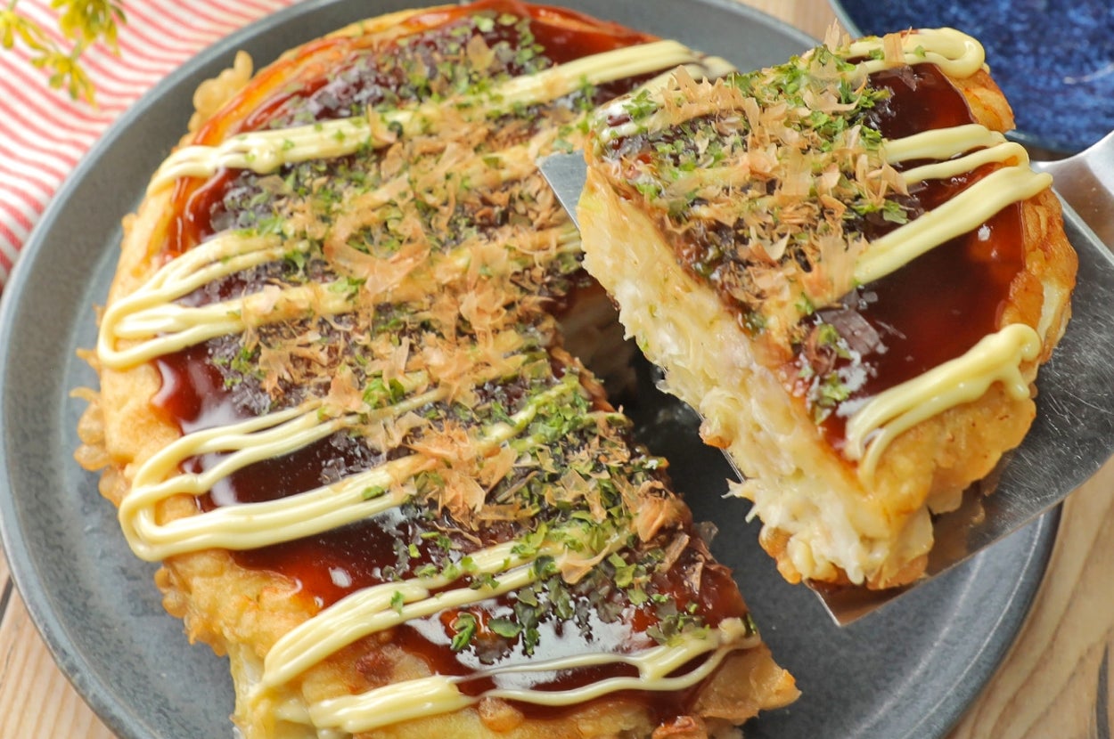 お好み焼きが皿に盛られており、上にソース、マヨネーズ、かつお節がトッピングされている。トッピングが食欲をそそる。