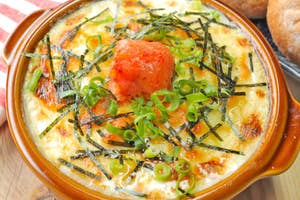 熱々の焼きおにぎり、海苔とネギがのった棒葉みそと一緒に陶器皿に盛られている。隣にパンが置かれている。