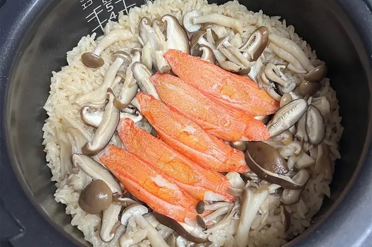 炊飯器の中に炊き込みご飯、サーモンときのこが乗っている。