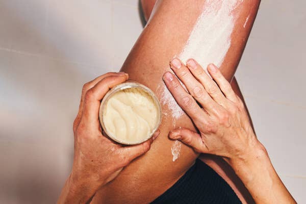 A person applies body scrub to their leg using their hands, emphasizing self-care and skincare ritual