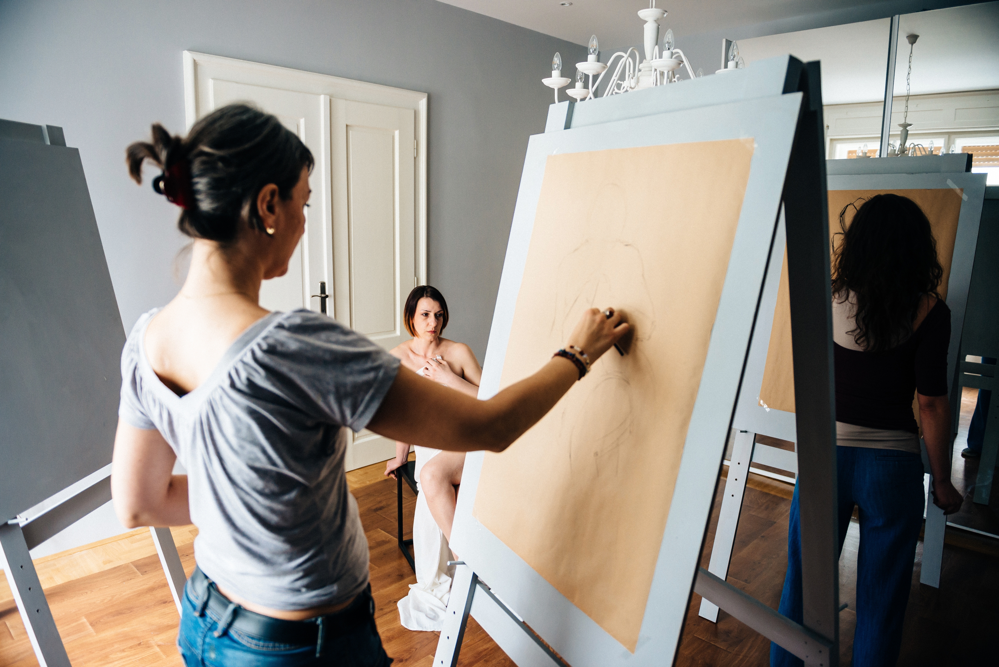Artists focus on drawing a model in a life drawing class, highlighting the intimate connection between art and the human form