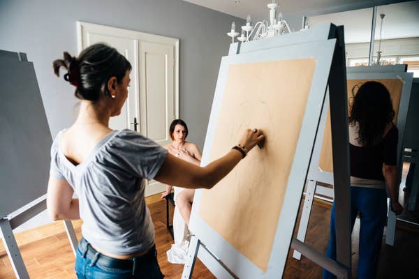 Artists focus on drawing a model in a life drawing class, highlighting the intimate connection between art and the human form