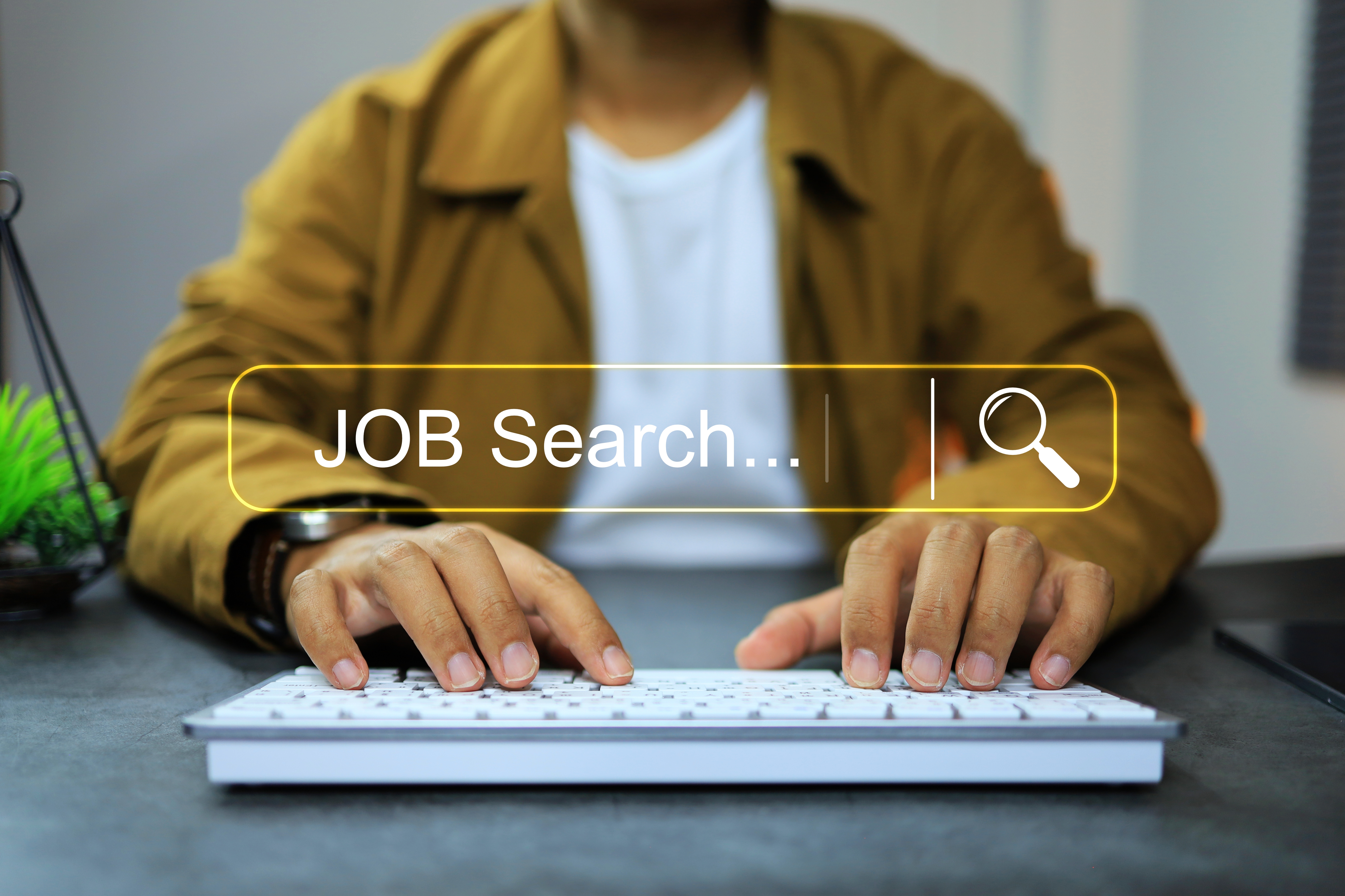 Person typing on a keyboard with a "Job Search" overlay, highlighting employment search efforts