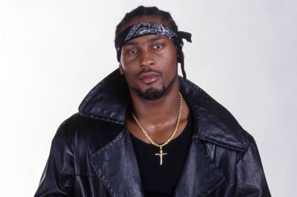 Individual wearing a leather jacket, gold chain, and bandana