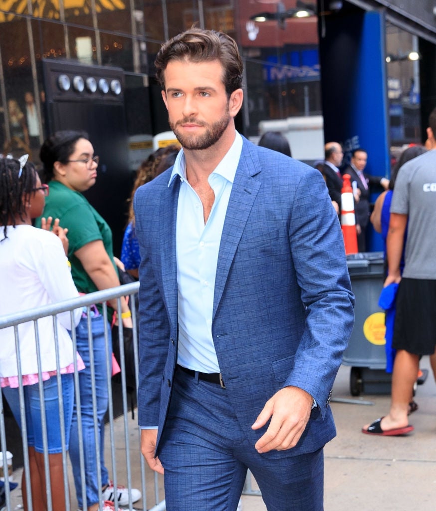 21 Low-Key Ridiculous Things Celebs Did For Money, Clout, Or Attention 110 Jed in a tailored suit walks outdoors, surrounded by onlookers behind a barrier