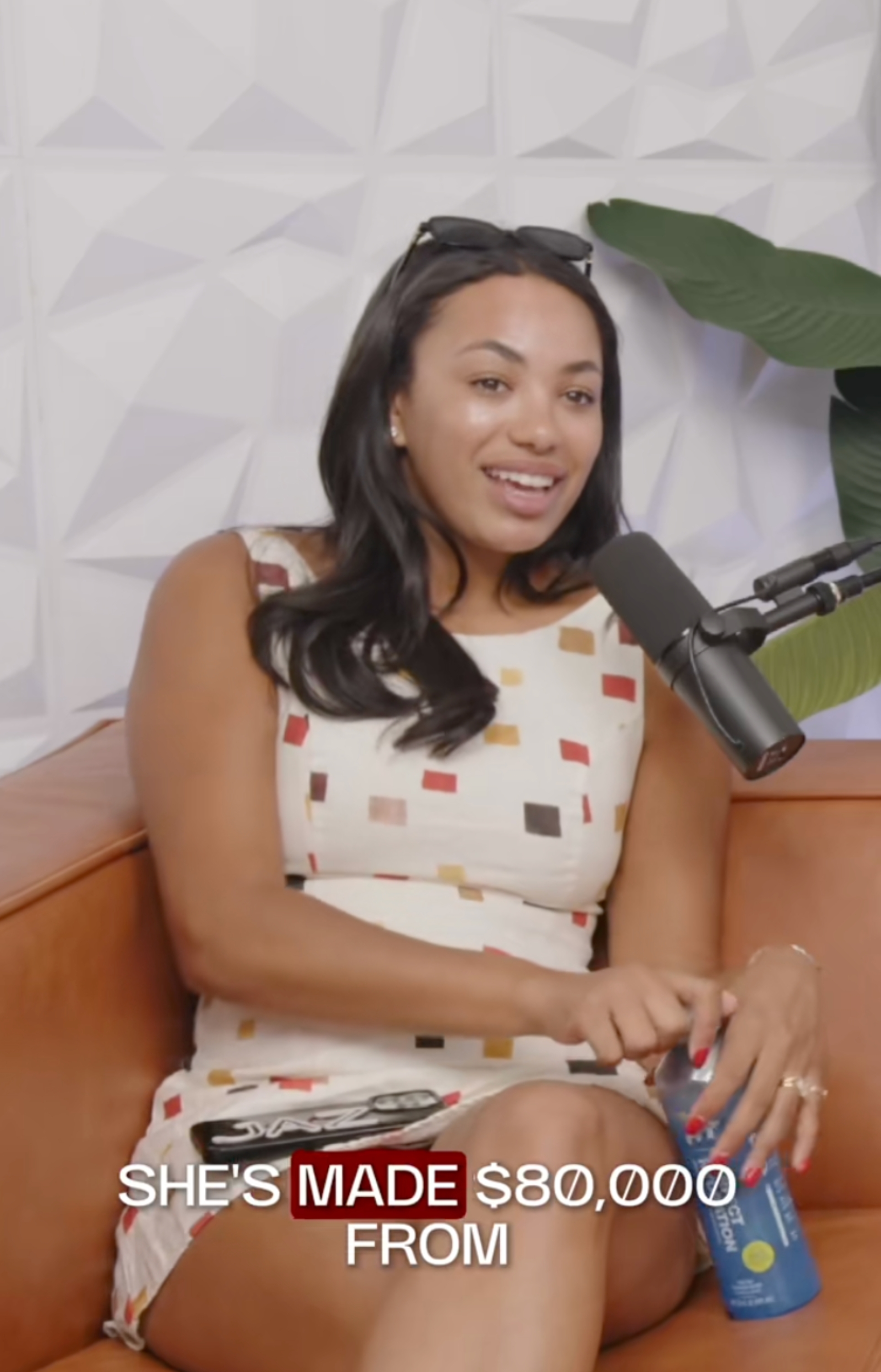 En person sitter på en sofa, iført en mønstret kjole, og snakker i en mikrofon. Teksten sier: 