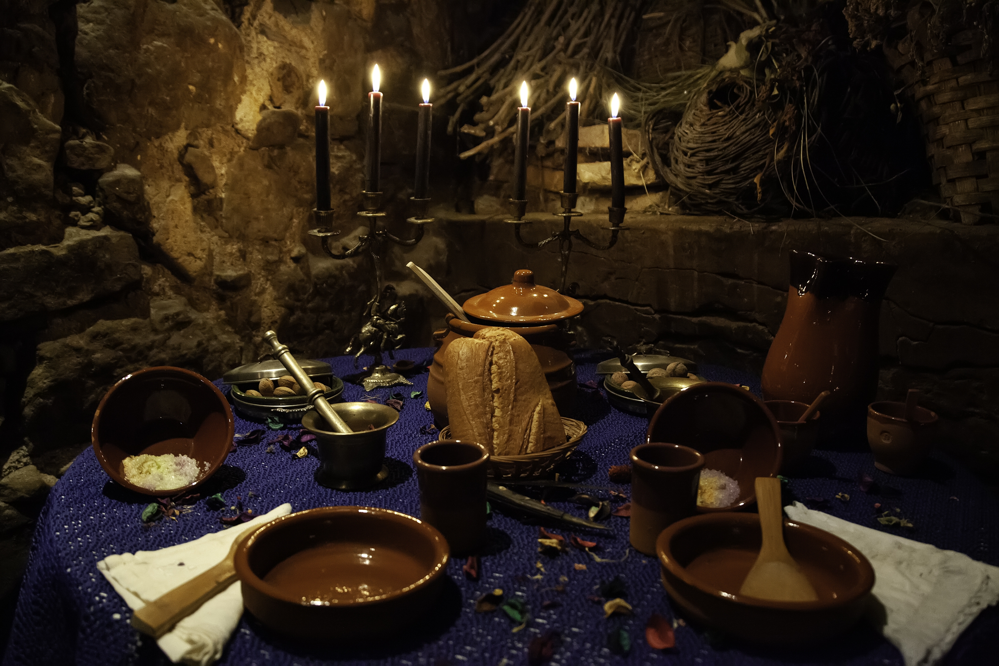 Et spiseoppsett i middelalderstil på et bord med boller, et brød, en morter og en stemning med levende lys