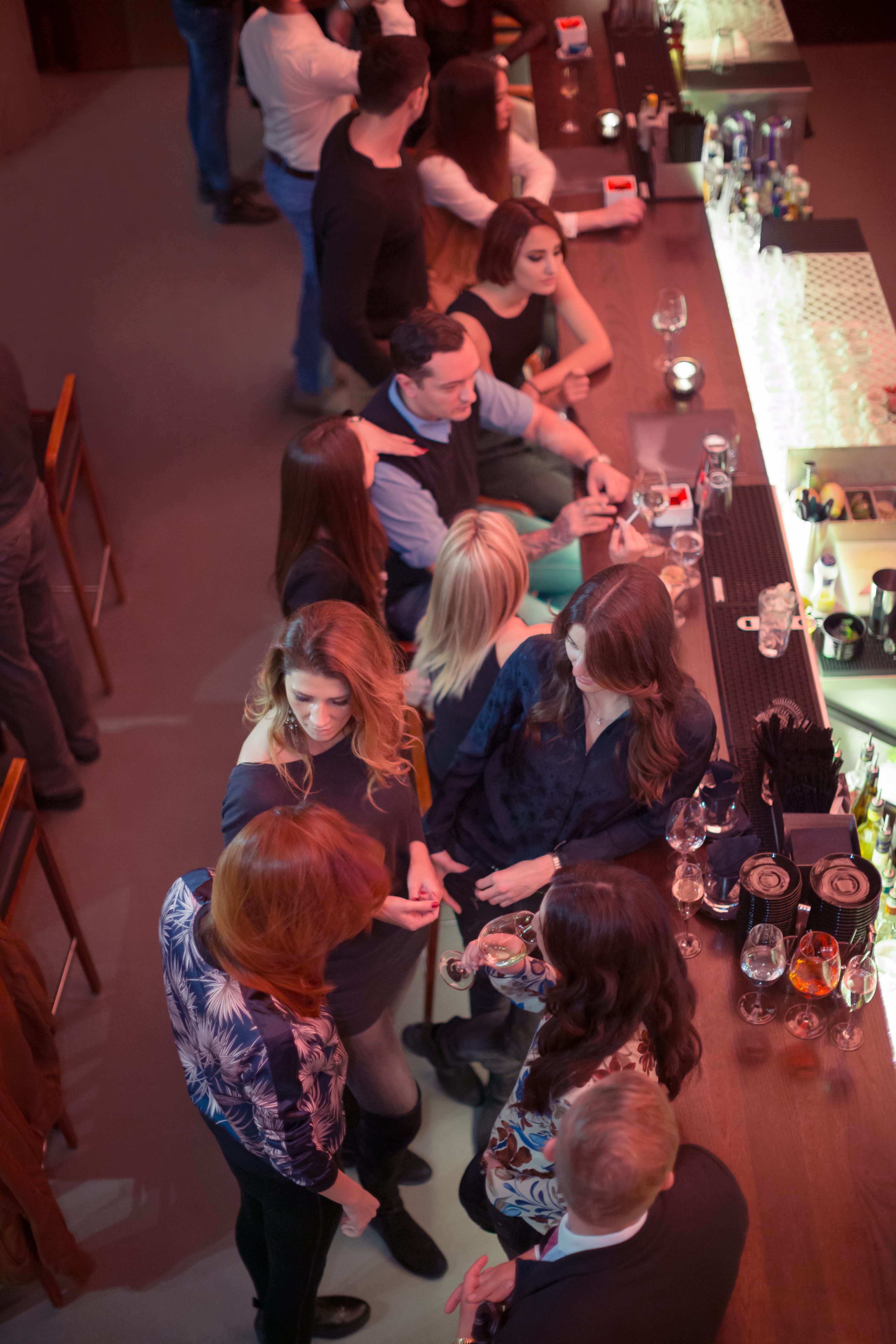 Folk som sosialiserer seg på en travel bar, sittende og stående, med drinker på disken