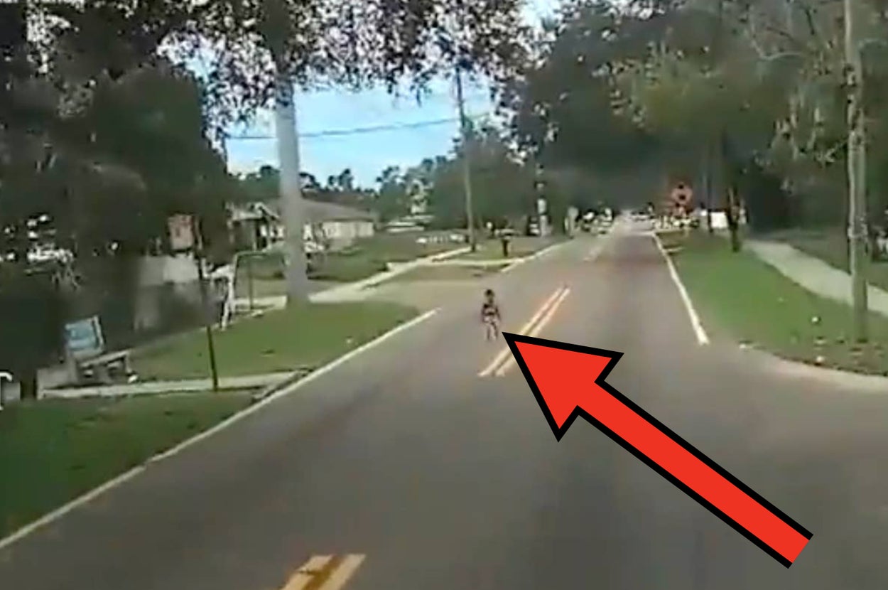 警報が表示された道路を歩く歩行者の映像。道路上に建物と車が見える。