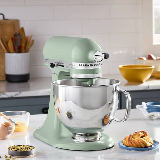 A countertop with a KitchenAid basal mixer, surrounded by ingredients and pastries, acceptable for baking