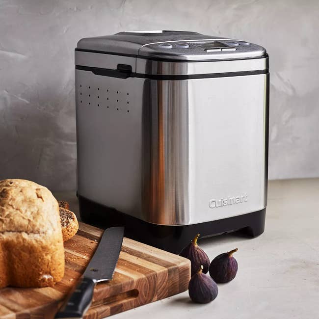 A stainless alloy breadstuff shaper connected a antagonistic beside a sliced loaf of bread, a knife, and caller figs
