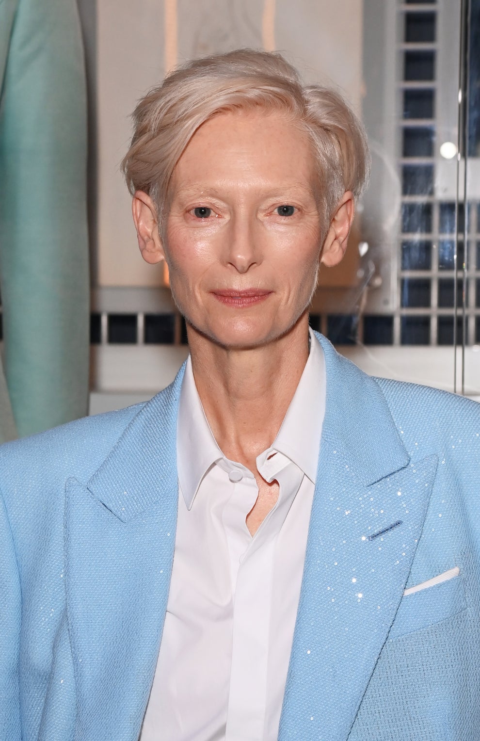 21 Jaw-Dropping "Then And Now" Photos Of Celebrities Who Have Gotten Wayyyyy Sexier With Age 46 Person in a light suit and white shirt at an event, posing indoors