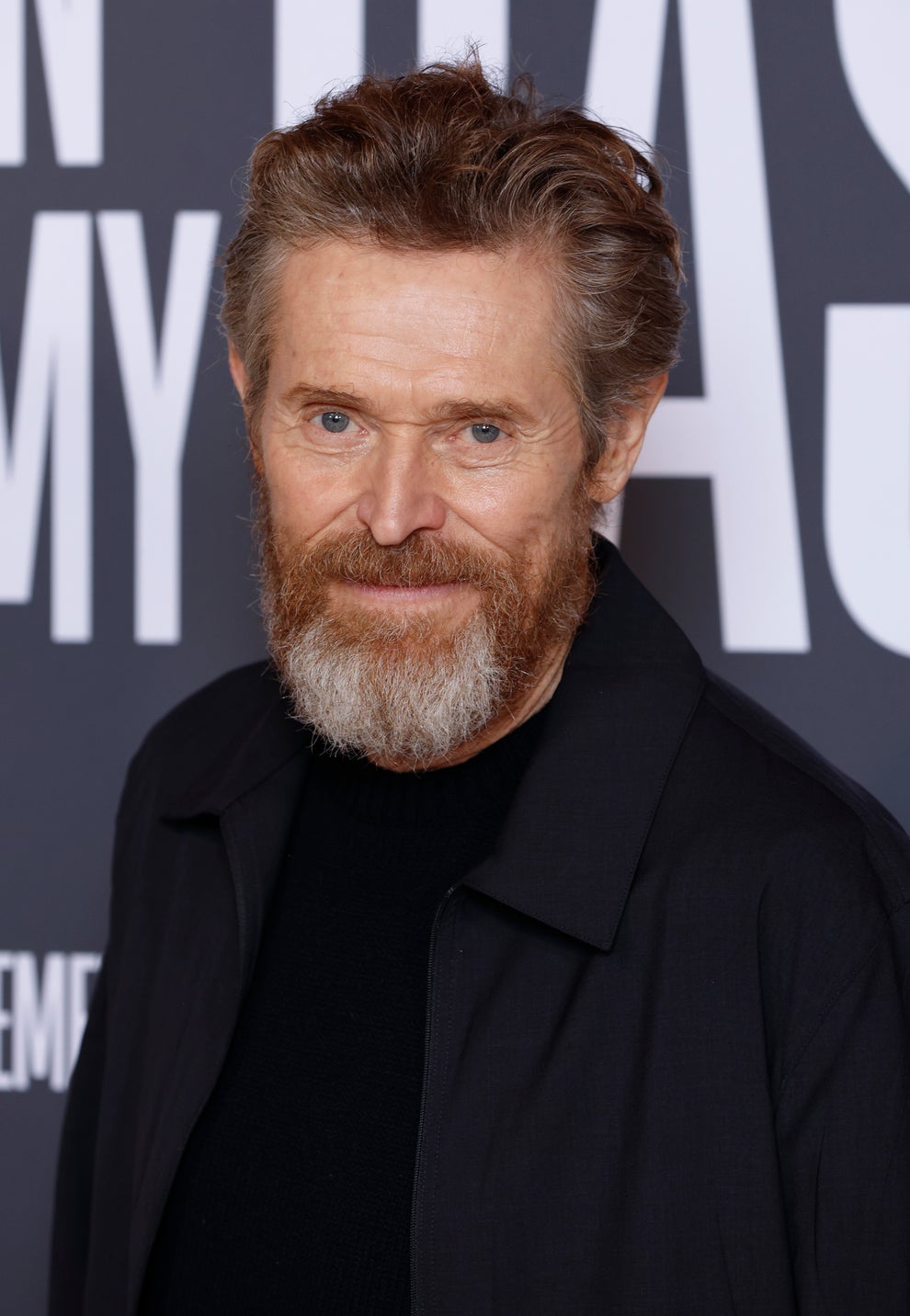 21 Jaw-Dropping "Then And Now" Photos Of Celebrities Who Have Gotten Wayyyyy Sexier With Age 60 Man with beard in a black jacket stands in front of a backdrop with large text