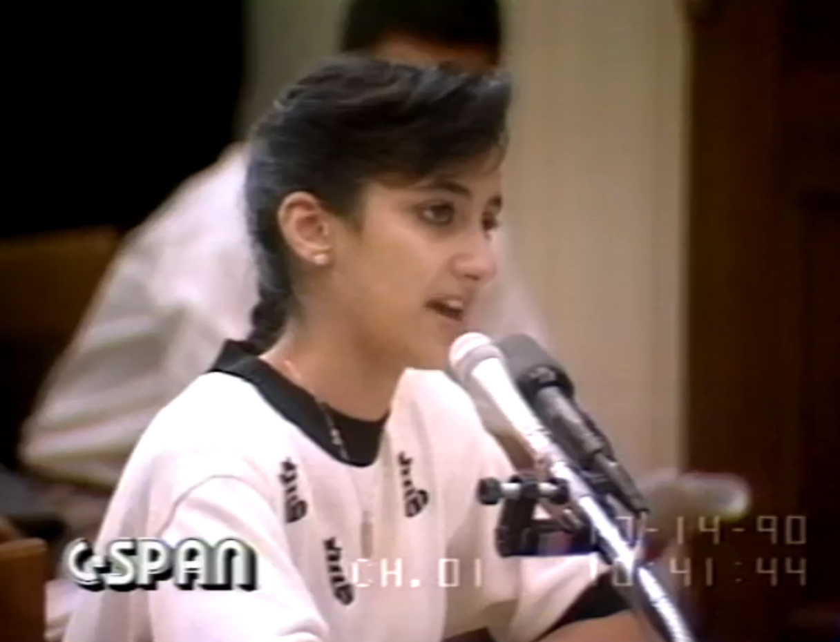 A young pistillate   speaks into a microphone astatine  a hearing