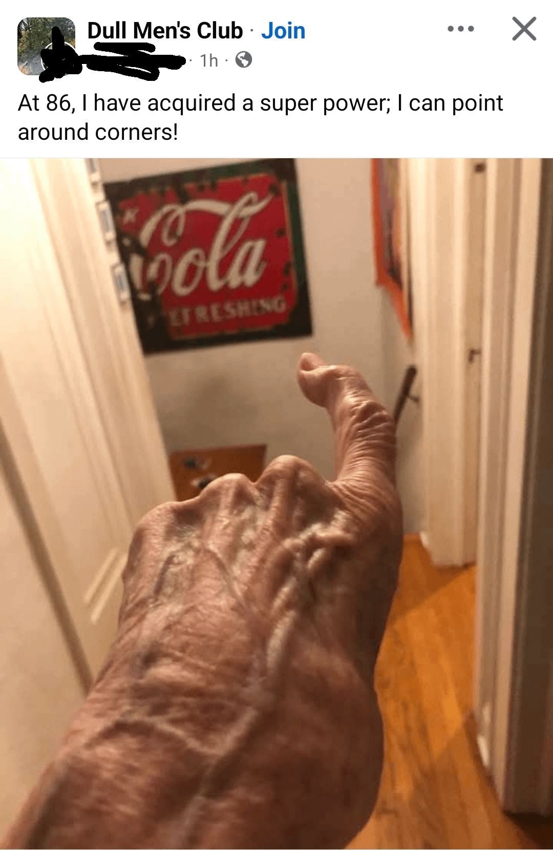 An elderly hand humorously points around a corner in a hallway, capturing a playful moment
