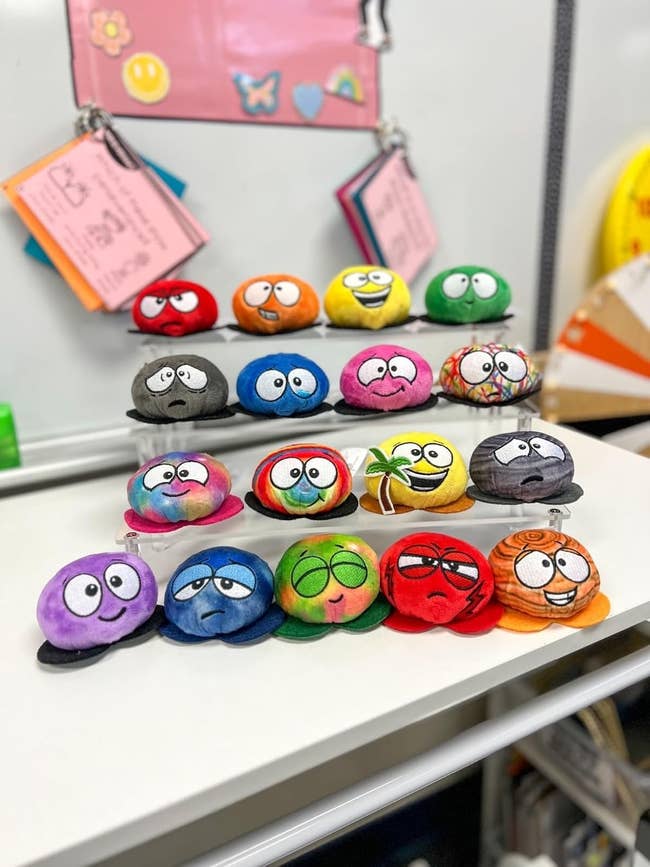 A show  of colorful accent   balls, each   with a unsocial   facial expression, arranged connected  a schoolroom  shelf