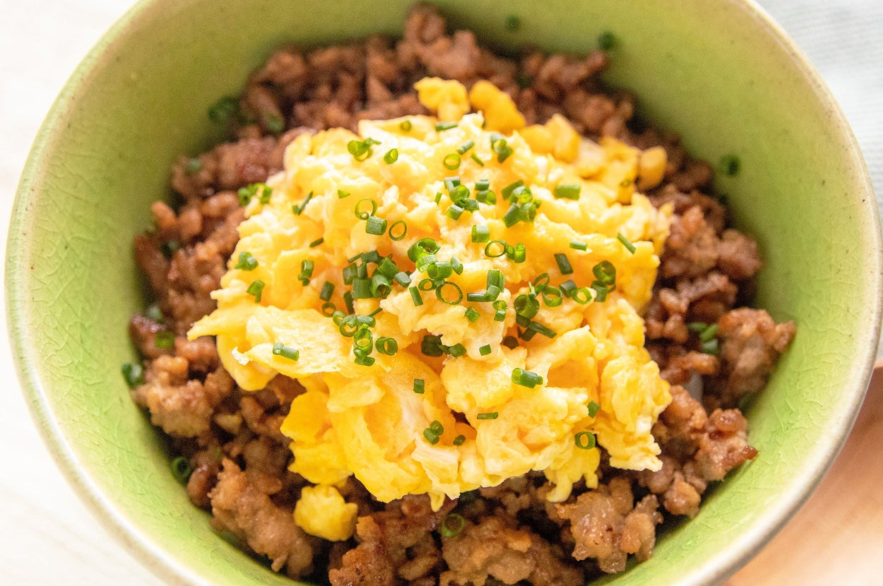 器に盛られた肉そぼろご飯の上に炒り卵と刻みネギがのっている料理。
