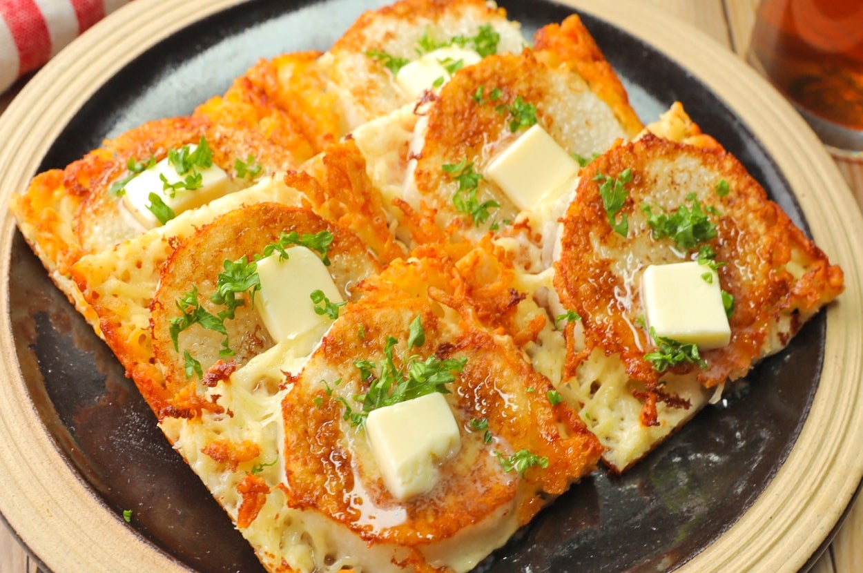 大根とバターがトッピングされた四角いピザ。テーブルクロスが背景。