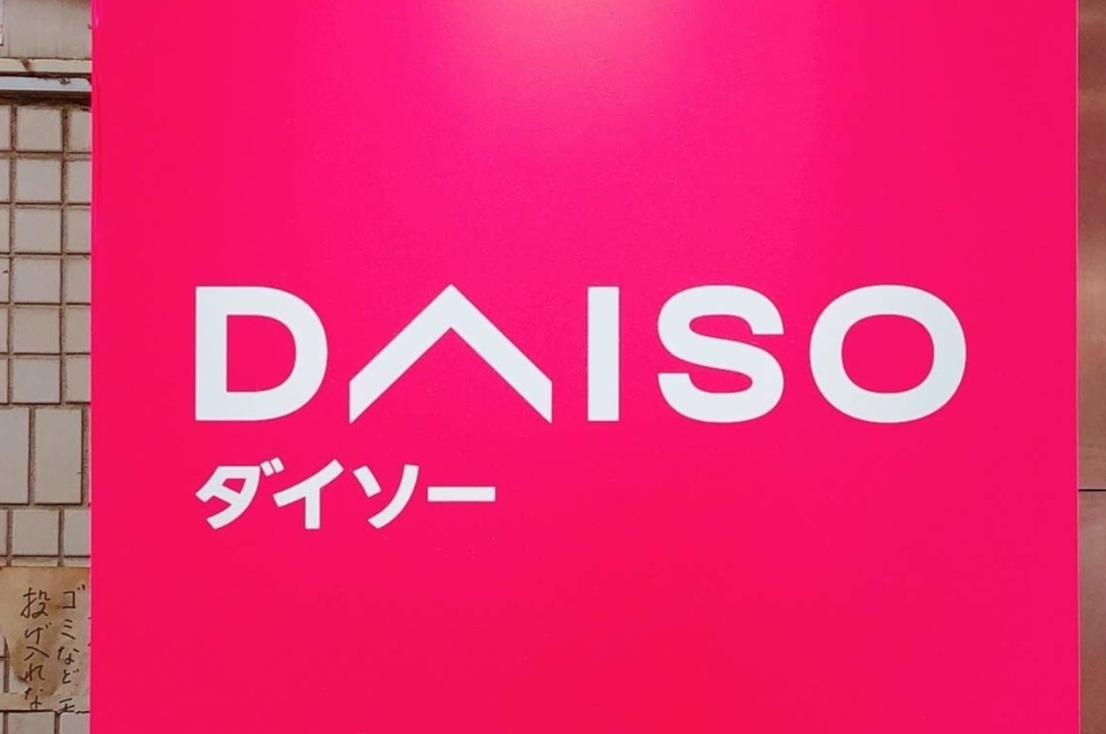 ダイソーのロゴ看板。白い壁にピンクの背景が目立つデザイン。