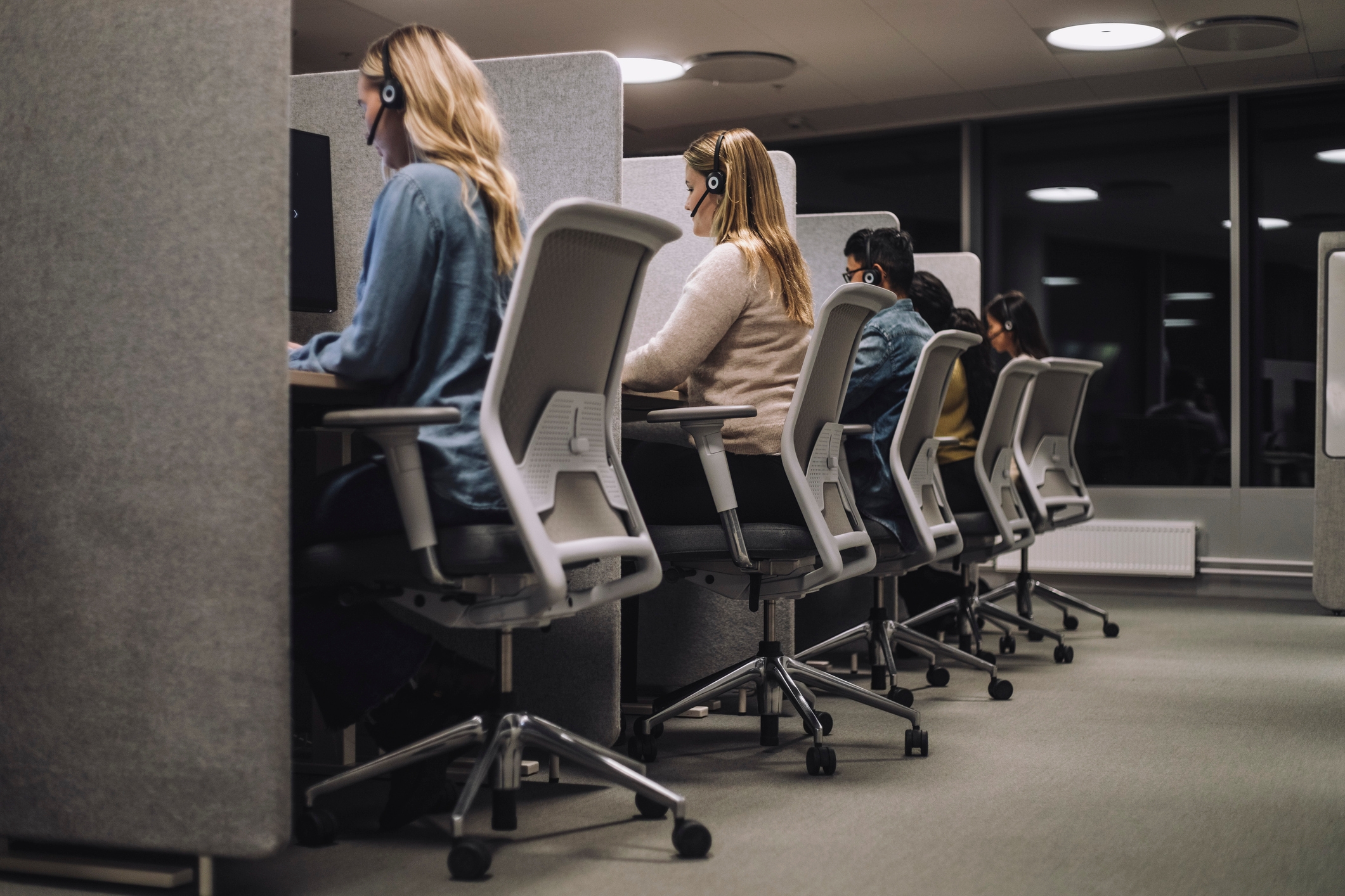 People working at call center desks, each wearing headsets