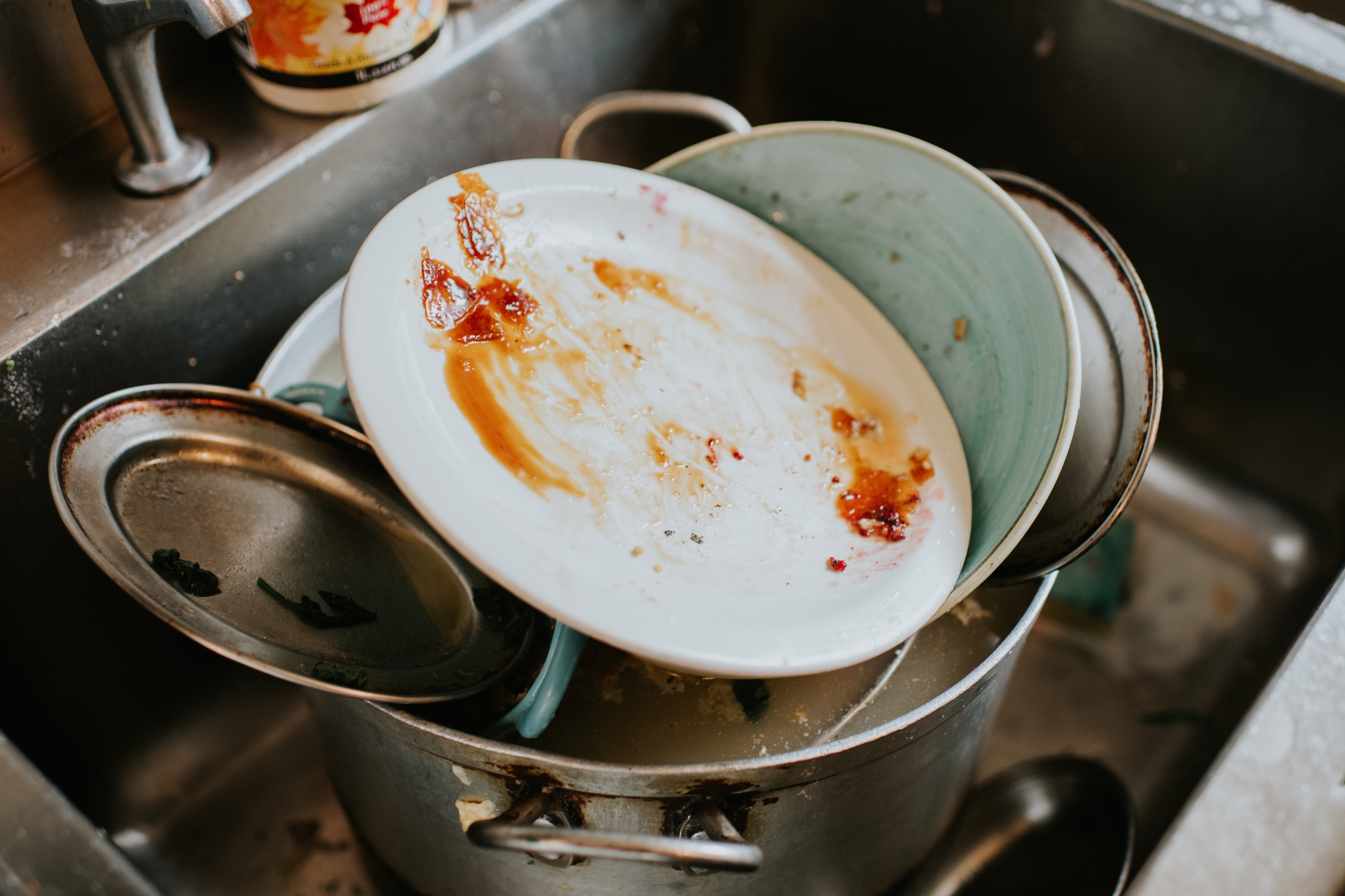 Sink filled with unwashed dishes and a pot, showing a cluttered kitchen space