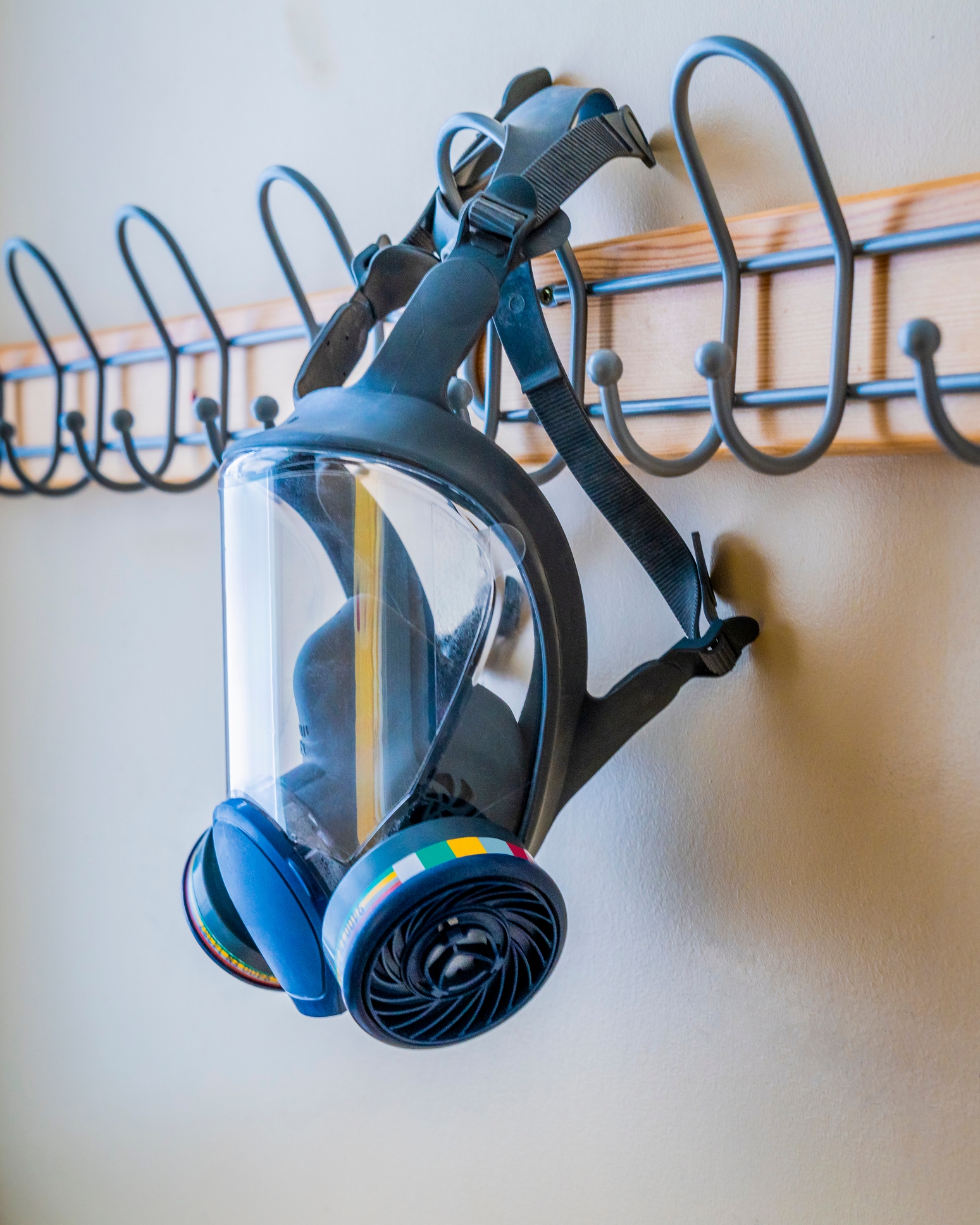 A full-face respirator mask hangs on a wall rack, implying workplace safety and preparedness