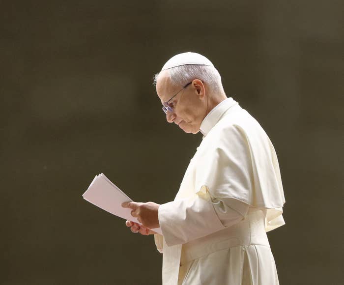 A person in religious attire, wearing a skullcap, reads a document intently
