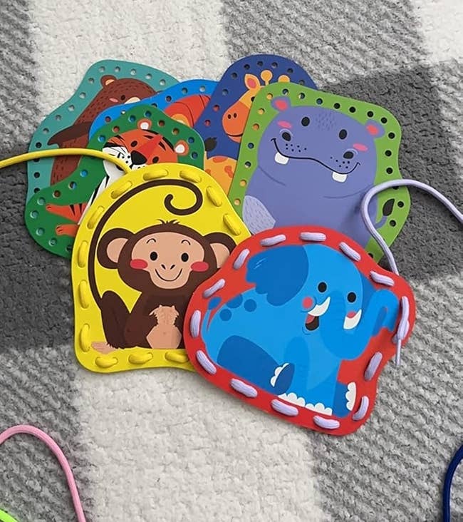 Colorful animal-themed lacing cards, featuring a monkey, elephant, and more, arranged connected a checkered surface. Suitable for children's activities