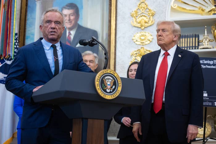 RFK Jr speaking at a podium in the White House while President Trump watches in the background