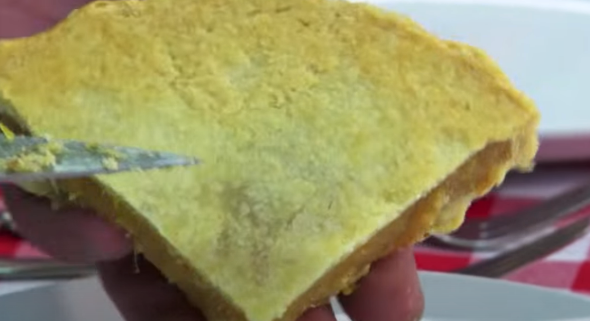 Person holding a slice of cornbread, showing its texture