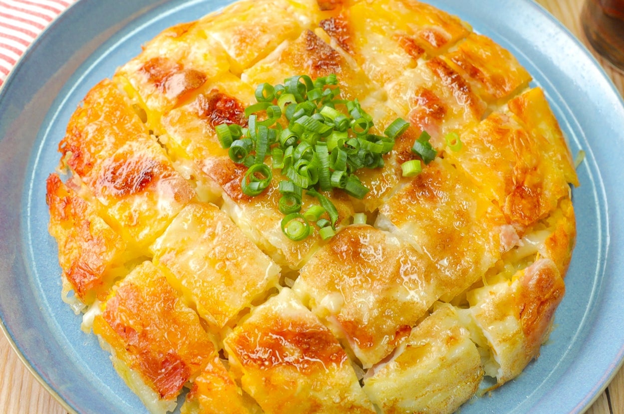 じゃがいもとチーズのガレット風料理が青い皿に乗っている。中央に刻んだネギが載せられている。