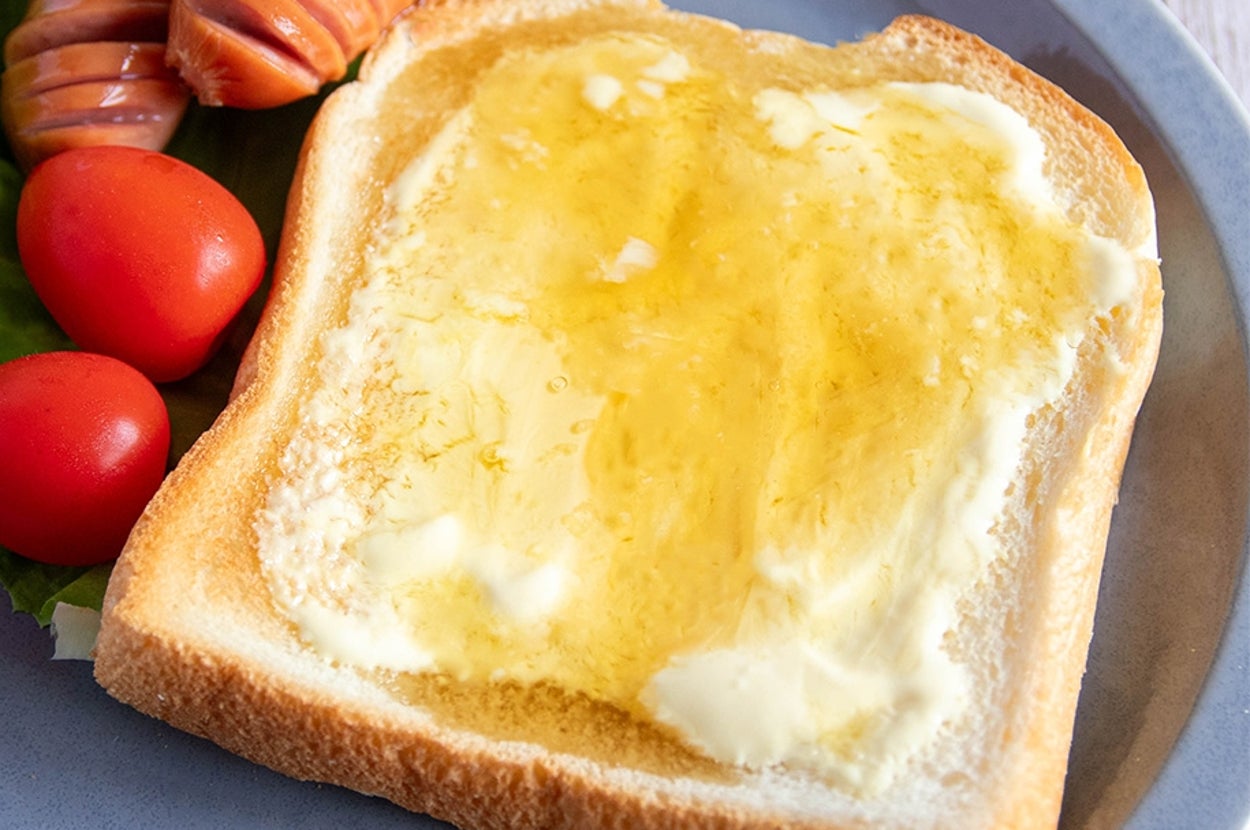トーストにマヨネーズとはちみつが塗られ、レタス、ミニトマト、ソーセージが添えられた朝食プレート。