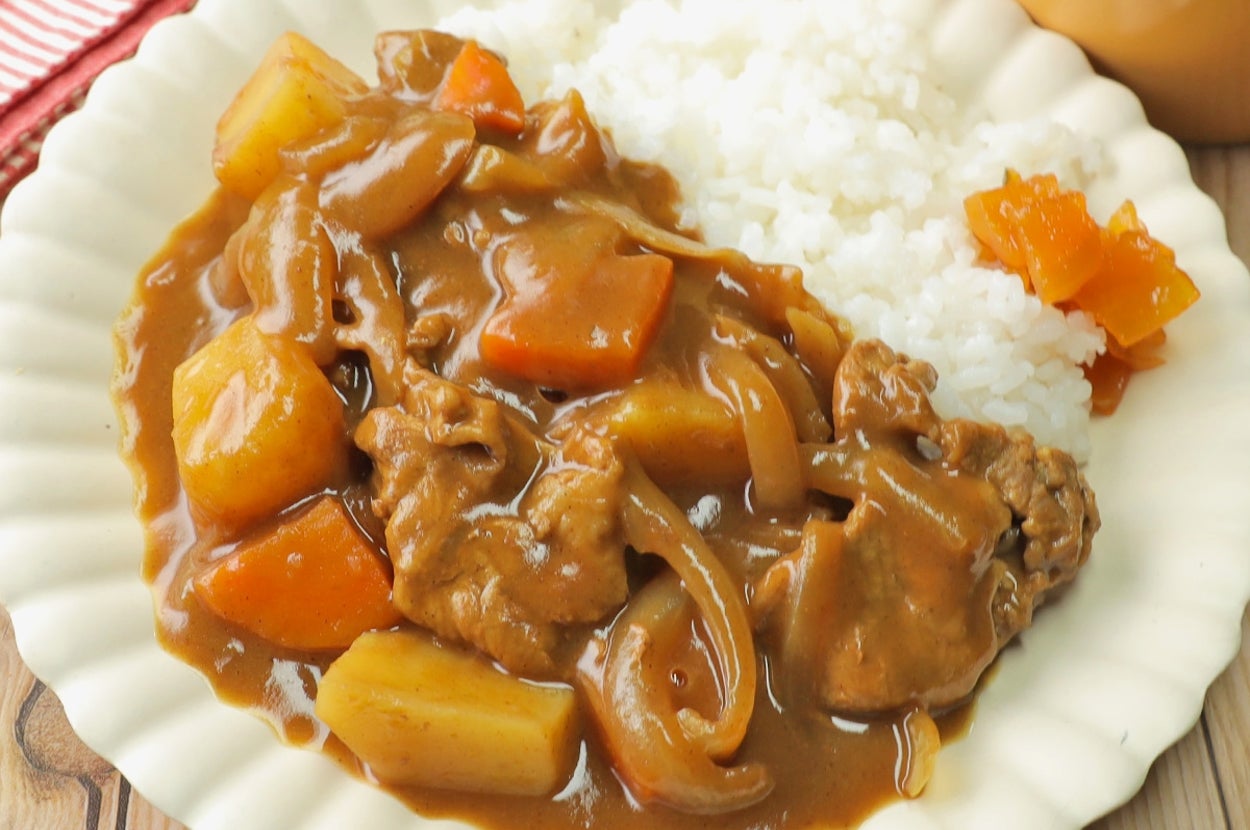 カレーライスと野菜の盛り合わせが白い皿に載せられている食事。スープ付き。