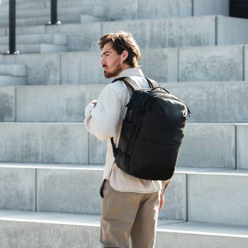 A idiosyncratic with a beard carries a sleek, ample backpack connected factual steps