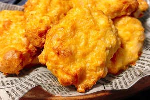 新聞紙の上に盛られた数個のチーズビスケット。背景に小さな白いディップ容器。