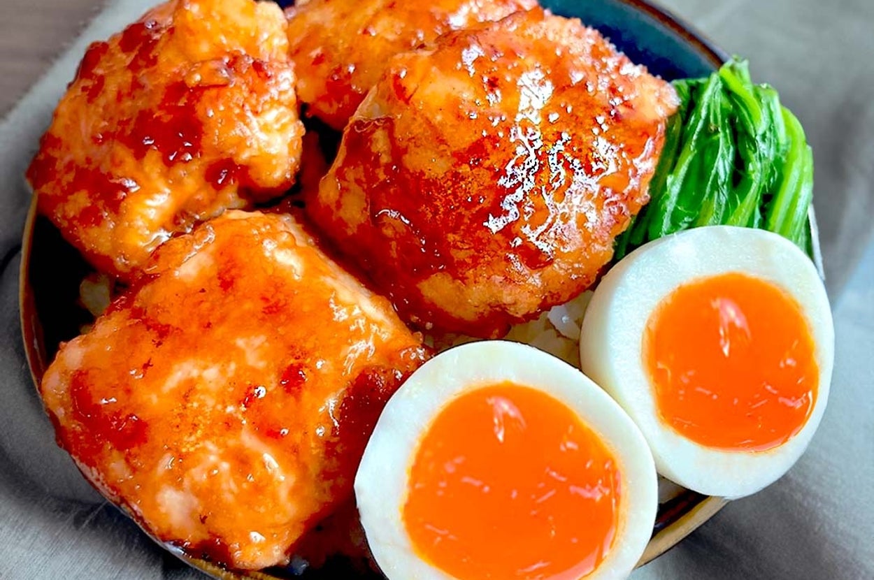 玉ねぎと醤油ソースをかけたチキンの上に、柔らかく茹でられた卵と青菜が添えられた料理の盛り付け。