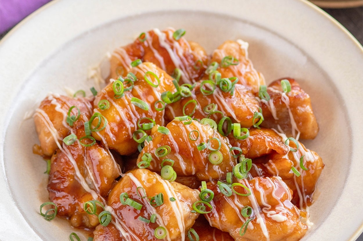 鶏肉の照り焼きが盛られた皿。青ネギとマヨネーズがかかっている。