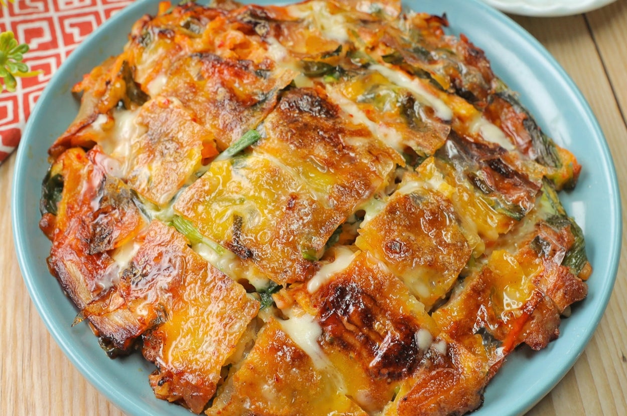 韓国風のチヂミが青い皿にのっている。小皿にはタレとゴマが添えられている。