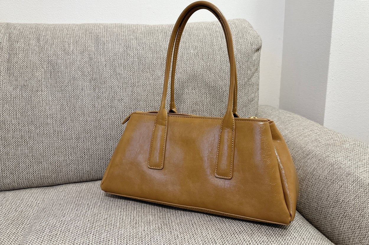 ソファに置かれた茶色のハンドバッグ。シンプルで上品なデザイン。