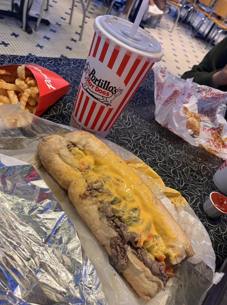 A hot dog with toppings and fries from Portillo's on a table in a casual dining setting. Reddit post asks for Chicago travel recommendations