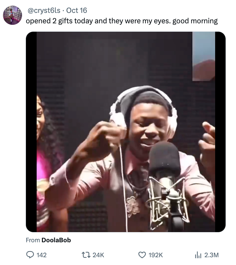 Person recording in a studio, wearing headphones and gesturing with their hands, another person partially visible beside them. Tweet text visible above