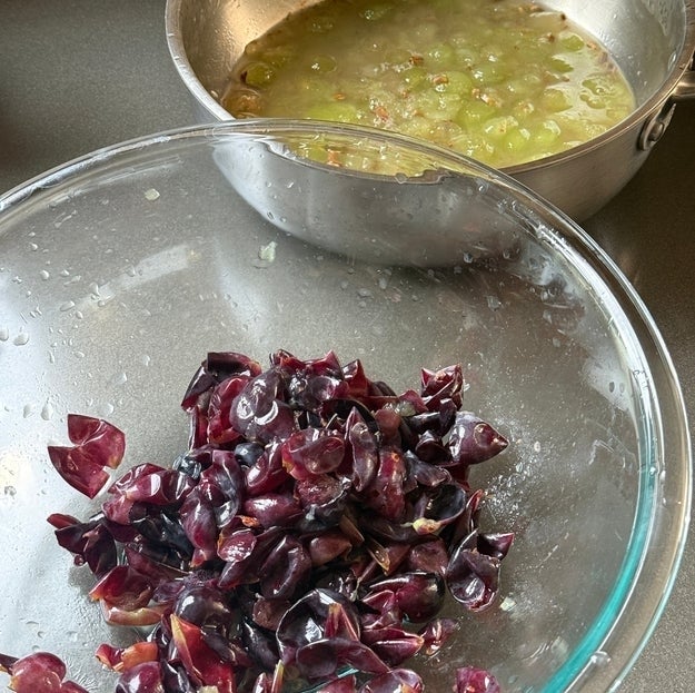 Chopped grapes in two bowls, one with green grapes in juice and another with purple grapes, ready for preparation
