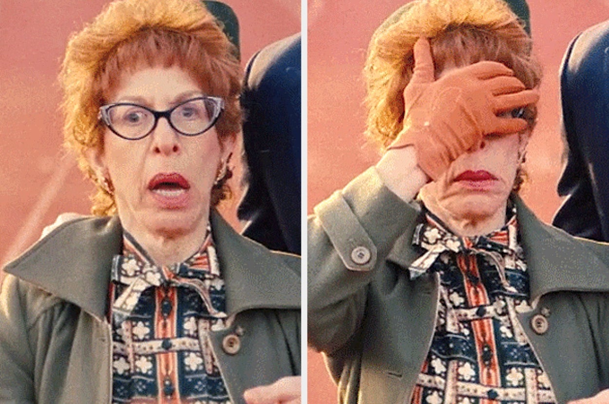 Person with surprised expression and glasses covers face with gloved hand. They wear a patterned blouse and coat